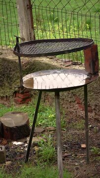 Tranquil image of a rustic barbecue grill in a garden with its base full of rainwater and some drops of it falling