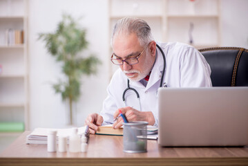 Old male doctor working in the clinic