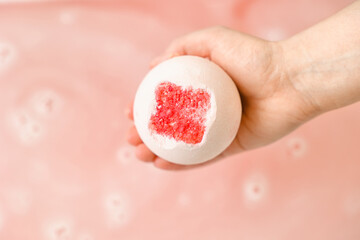Fototapeta premium Woman with bath bomb above water in room, closeup