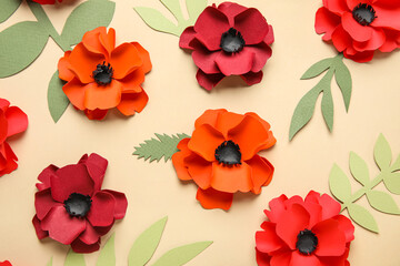 Paper poppy flowers with leaves on beige background