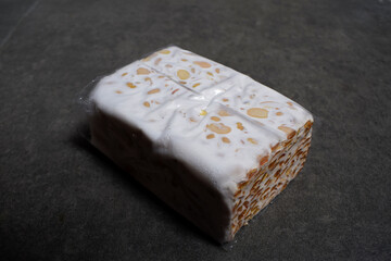 Photo of raw tempeh wrapped in plastic on a dark background.