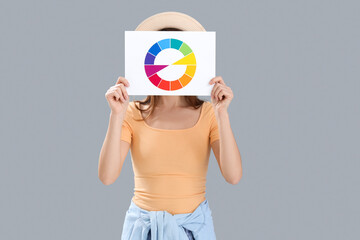 Young woman with paint color palette on grey background