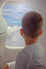 Back view of little boy looking aerial view of sky and cloud outside airplane window.Traveling concept background - 582736746