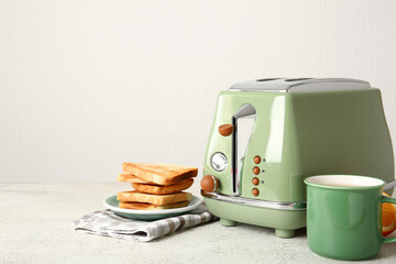 Modern toaster, toasts and cup of juice on white table