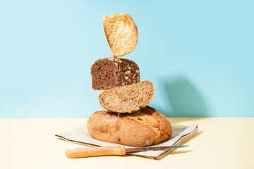 Loaves of different bread and knife on beige table near blue wall