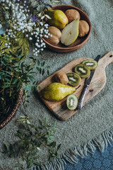 still life of pear and kiwi on the table with a vase of flowers
