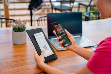 Woman using contactless payment by mobile phone with QR code at cafe