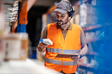 A delivery center worker with modern equipment is inventorying in storage.