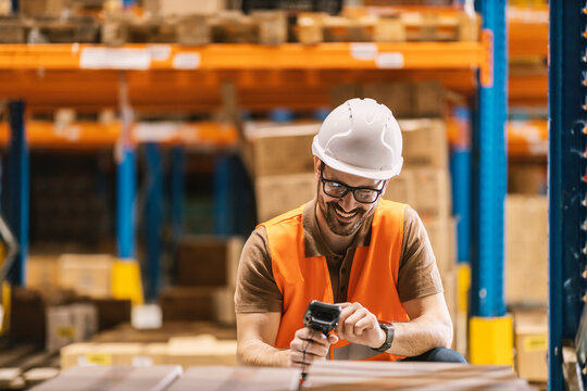 A delivery center worker is using bar code reader on boxes.