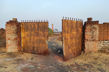 The old outer wall and broken iron gate of an abandoned factory