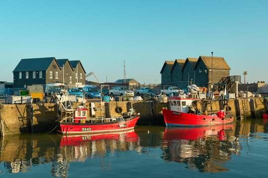 Fishing boats docked in Whitstable harbor on a sunny day