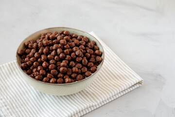 Chocolate Puff Cereal with Milk in a Bowl, side view. Copy space.