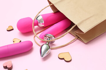 Shopping bag with sex toys and wooden hearts on pink background