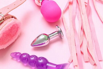 Different sex toys on pink background, closeup