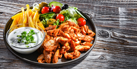 Kebab served with french fries, vegetable salad and tzatziki