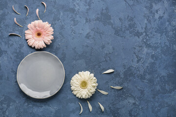 Table setting with beautiful gerbera flowers on blue grunge background