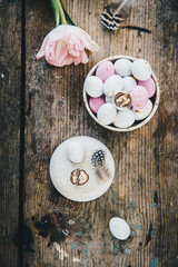 White and pink chocolate eggs and pink tulips on rustic wooden table.