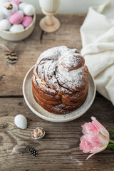 Homemade Easter bread (cruffin), chocolate eggs and pink tulips on old wooden table.