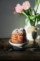 Homemade Easter bread (cruffin), egg shaped wax candle and pink tulips on old wooden table.