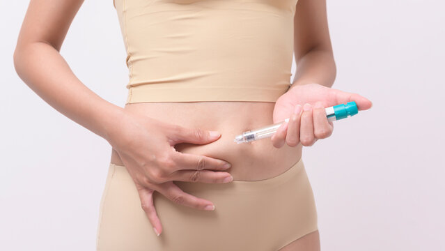 Close up woman using IVF treatment injection on belly to prepare reproductive fertility , Ovulation stimulation ..