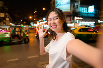 Beautiful young Asian tourist woman on vacation sightseeing and exploring at Khao San road at night in Bangkok city, Thailand, Holidays and traveling concept