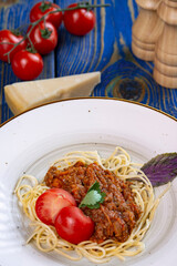 Pasta with meat, tomato sauce and vegetables in blue wooden desk