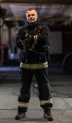 Firefighter wearing full equipment and emergency rescue equipment wiht oxygen mask Fire trucks in the background.