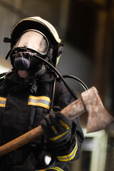 Naklejka premium Female firefighter portrait wearing full equipment with oxygen mask and an axe.
