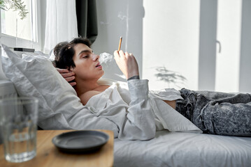 handsome man smoking blunt with medical cannabis in apartment.heavy smoker spend time in the...