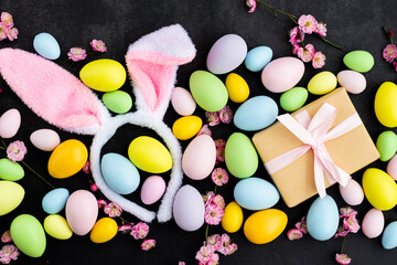 Stylish background with colorful easter eggs on dark concrete background with blooming branches of...