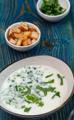 yogurt soup with herbs and crackers on a blue wooden table