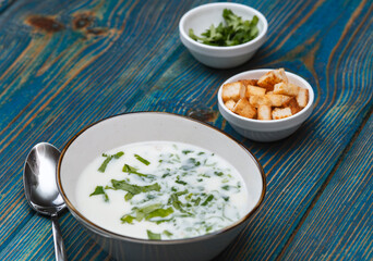 yogurt soup with herbs and crackers on a blue wooden table