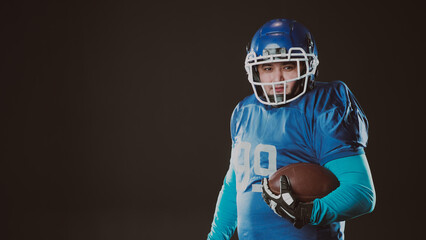 Portrait of a man in a blue uniform for american football on a black background. 