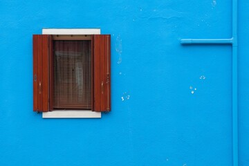 Red window of blue building in Venice