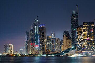Cityscape of Dubai at night with boats and skyscrapers