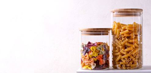 Web banner with two pasta types: farfalle and macaroni in glass jars on white background. Mockup with copy space
