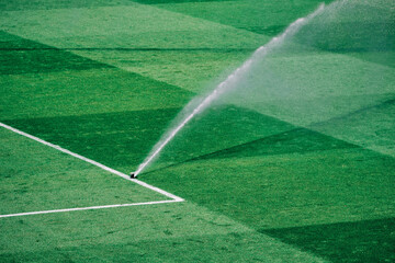 Keeping the pitch perfect: sprinkler in action on a hot day - obrazy, fototapety, plakaty
