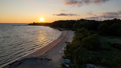 Aerial view of a golden sunrise on the gold coast of Long Island, New York, over an empty beach. © Audley C Bullock/Wirestock Creators