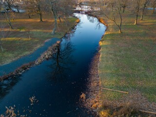 Aerial view over a quiet park with a lake at sunrise