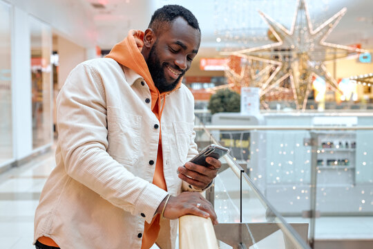 cheerful guy chatting with his girlfriend at business office. handsome joyful man enjoys sending message, texting sms, looking at the screen of cell phone, pleasanat conversation with c olleague