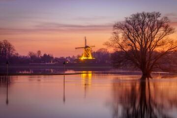 Fototapeta na wymiar Scenic view of a calm waters with luminated old windmill in the background
