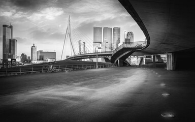 Grayscale shot of the beautiful architecture of the Erasmusbrug bridge seen during the sunset