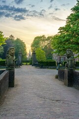Vertical closeup shot of a pathway in an old park with statues, on a sunny day
