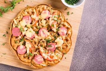 Closeup of waffle pizza with tomatoes, sausages, cheese and herbs on a wooden board. Top view