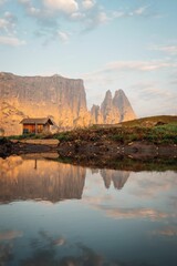Fototapeta na wymiar Old wooden hut and rocky mountains of South Tyrol reflected on a lake during the sunset