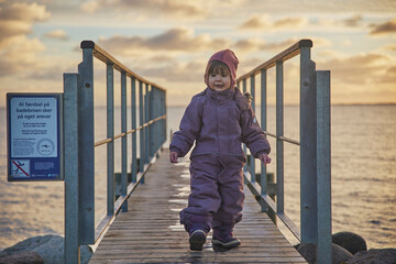 Adorable child walking on the pier in the evening in Denmark