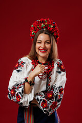 Portrait of ukrainian woman in traditional ethnic clothing and floral red wreath on viva magenta studio background. Ukrainian national embroidered dress call vyshyvanka. Pray for Ukraine