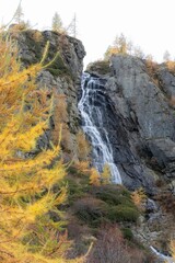 Vertical view of a waterfall over a rocky cliff in autumn