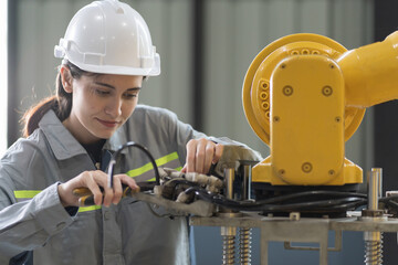 Industrial Robotic Arms. Automated manufacturing industries. Female engineer using equipment tools, checking, repair, maintenance autonomous robotics arms for manufacturing lines in workshop