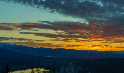 Fiery dawn over Fraser Valley, BC, from sun rising behind alpine mountains on horizon.